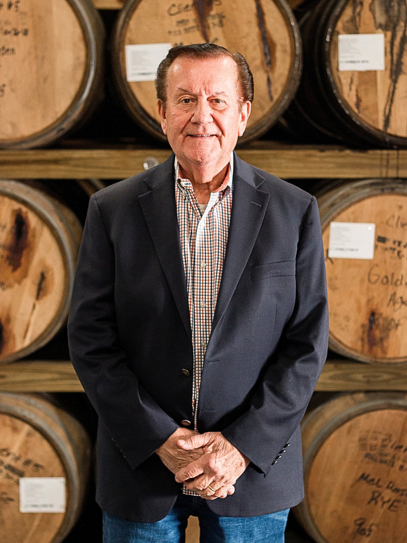 J.W. Kelly team member standing among whiskey barrels