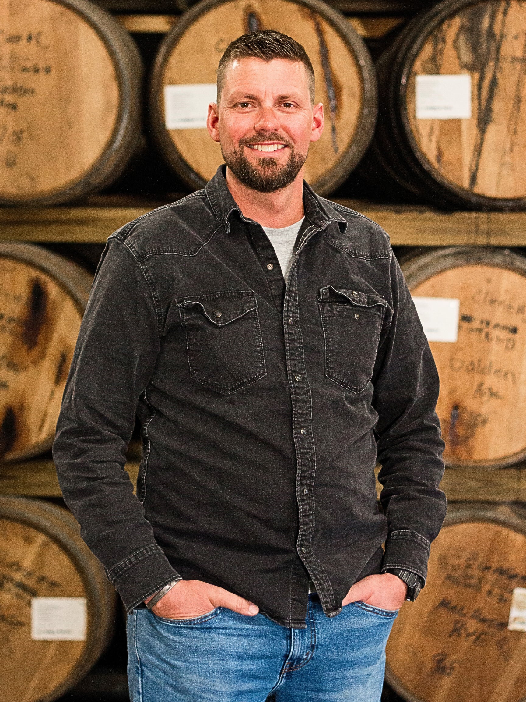 Justin Brumbaugh standing in front of stacked barrels