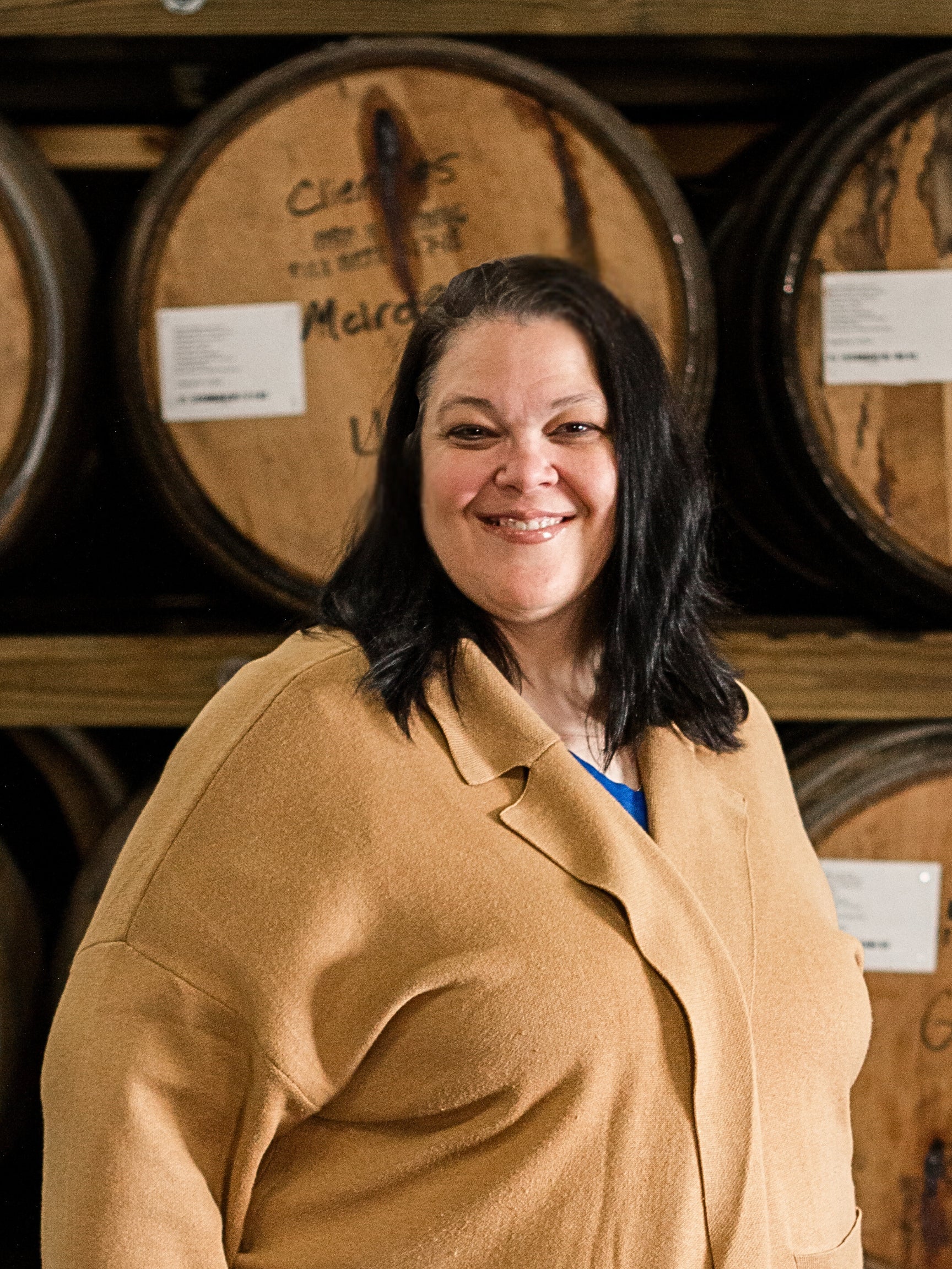 Leslie Sampson standing in front of stacked barrels